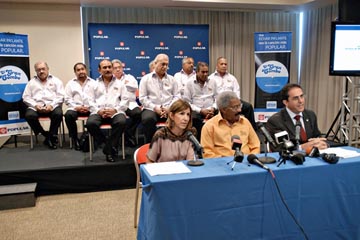 Mariel Arraiza, Rafael Ithier, and Eduardo Negrón offer details of Popular's new ad campaign, as member of El Gran Combo look on.