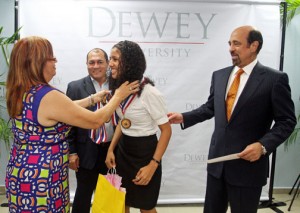 One of this year's outstanding students receives an achievement medal, as  Dewey University President Carlos Quiñones-Alfonso (right) looks on.