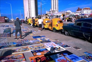 Paintings are spread out for sale at an outdoor flea market along Havana’s oceanfront Malecón. (Credit: Larry Luxner)