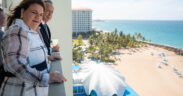 Businessman John Paulson and Puerto Rico Gov. Jenniffer González overlook the beach and iconic seashell-shaped structure at La Concha Resort in San Juan.