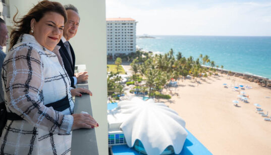 Businessman John Paulson and Puerto Rico Gov. Jenniffer González overlook the beach and iconic seashell-shaped structure at La Concha Resort in San Juan.
