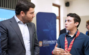 Sebastián Negrón-Reichard, secretary of the Department of Economic Development and Commerce, speaks with a student involved in developing the Interactive Map of Puerto Rico’s Logistics and Cargo Ecosystem.