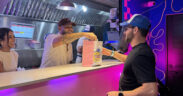 From left: Grace Martínez and Alex García-González, founder of Flatbelgel and El Colmadito de En La Madre, hand over a dish to a customer at 129 Gastropark in Arecibo, Puerto Rico, during the restaurants’ opening weekend.