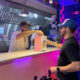 From left: Grace Martínez and Alex García-González, founder of Flatbelgel and El Colmadito de En La Madre, hand over a dish to a customer at 129 Gastropark in Arecibo, Puerto Rico, during the restaurants’ opening weekend.