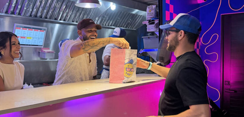 From left: Grace Martínez and Alex García-González, founder of Flatbelgel and El Colmadito de En La Madre, hand over a dish to a customer at 129 Gastropark in Arecibo, Puerto Rico, during the restaurants’ opening weekend.