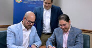 Josué E. Rivera, president of the Puerto Rico Economic Development Bank, stands as physicians Juan Nieves and Félix Álvarez sign a nearly $1.4 million loan agreement to expand Puerto Rico Cardiology LLC.