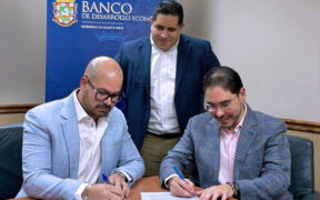 Josué E. Rivera, president of the Puerto Rico Economic Development Bank, stands as physicians Juan Nieves and Félix Álvarez sign a nearly $1.4 million loan agreement to expand Puerto Rico Cardiology LLC.