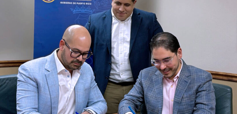 Josué E. Rivera, president of the Puerto Rico Economic Development Bank, stands as physicians Juan Nieves and Félix Álvarez sign a nearly $1.4 million loan agreement to expand Puerto Rico Cardiology LLC.